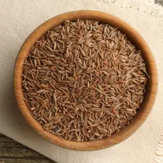 Drewniana miseczka pełna nasion kuminu i kminku, przypraw o intensywnym aromacie, gotowych do dodania smaku potrawom.
