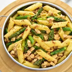Penne z kurczakiem i szparagami, posypane papryką. Pyszne danie, które zachwyci każdego smakosza.