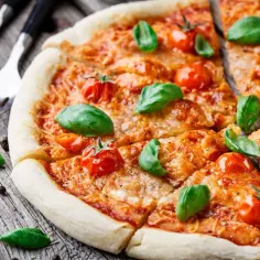 Pyszna pizza Margherita z pomidorkami i bazylią, klasyka włoskich dań, gotowa do podania.