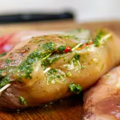 Kurczak faszerowany zielonym pesto, gotowy do pieczenia. Aromatyczne zioła i przyprawy podkreślą smak dania.