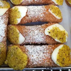 Chrupiące rurki wypełnione kremem, posypane cukrem pudrem i pistacjami. Pyszne cannoli czekają na spróbowanie!