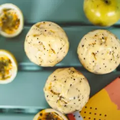 Jak zrobić sorbet z marakui? Kilka gałek pysznego, domowego sorbetu z owoców marakui, obok przekrojonych owoców i zielonej marakui.