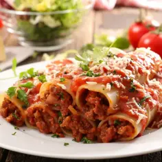 Pyszne cannelloni z mięsem mielonym, polane sosem pomidorowym i posypane parmezanem, na tle świeżych pomidorów i sałatki.
