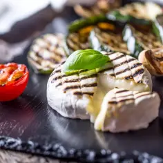 Pyszny camembert z grilla, podany z grillowanymi warzywami i pomidorkami. Idealna przekąska na lato.