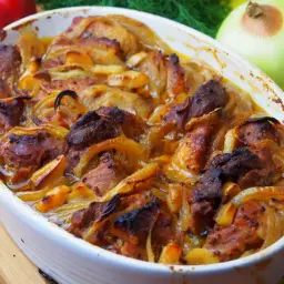 Pyszna łopatka pieczona z cebulą w białym naczyniu żaroodpornym. Mięso jest soczyste, a cebula zeszkolona.