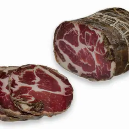 Pokrojona i cała coppa, wędlina o charakterystycznym marmurkowym wzorze, gotowa do degustacji.