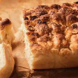 Puszysta, złocista focaccia z oliwkami i rozmarynem, idealna na oryginalny włoski przepis.