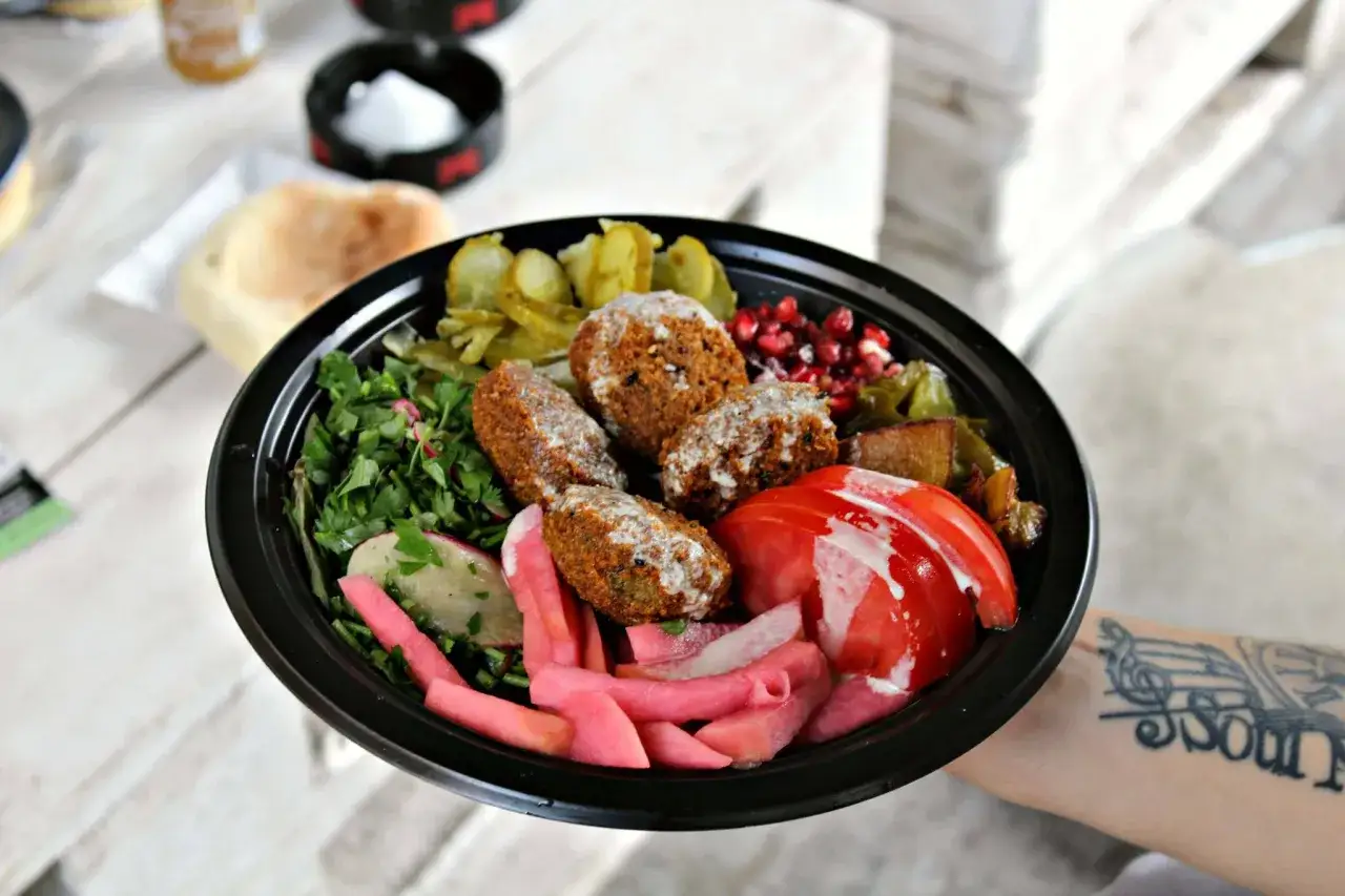 Misternie ułożony falafel co to? Aromatyczne kulki z ciecierzycy, świeża pietruszka, pikle, pomidor i sos. Pyszne danie.
