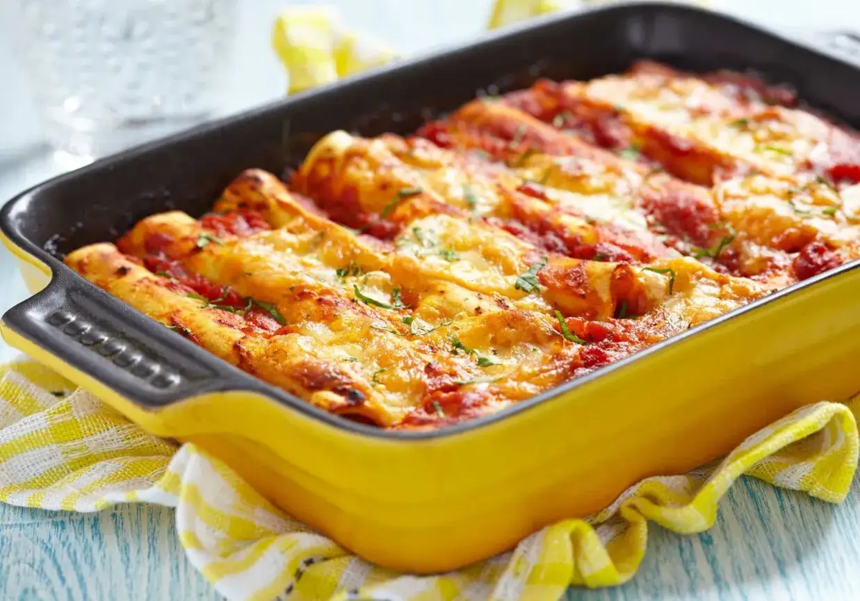 Pyszne cannelloni z mięsem mielonym, zapieczone pod sosem pomidorowym i serem, w żółtej naczyniu żaroodpornym.