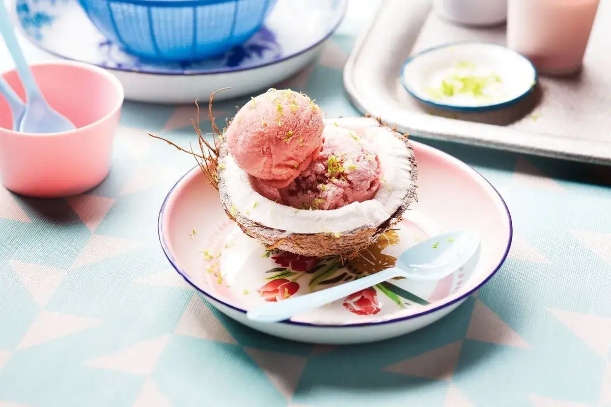 Jak zrobić sorbet? Pyszny, różowy sorbet z malin podany w połówce kokosa, posypany skórką z limonki. Idealny na upalne dni!