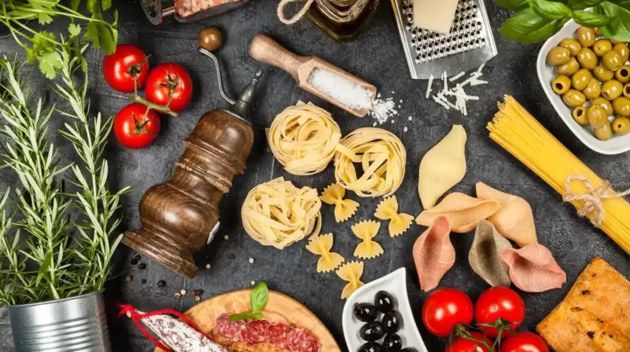 Składniki na pyszne włoskie dania: makarony, pomidory, oliwki, bazylia, rozmaryn, ser i salami.