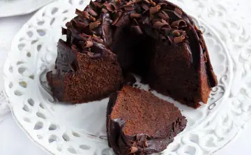 Pyszna babka z mascarpone i kakao, oblana czekoladą i posypana wiórkami. Idealna na deser.