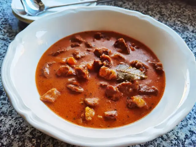 Gulasz z łopatki wieprzowej w sosie własnym, aromatyczny i sycący, podany w białej misce.